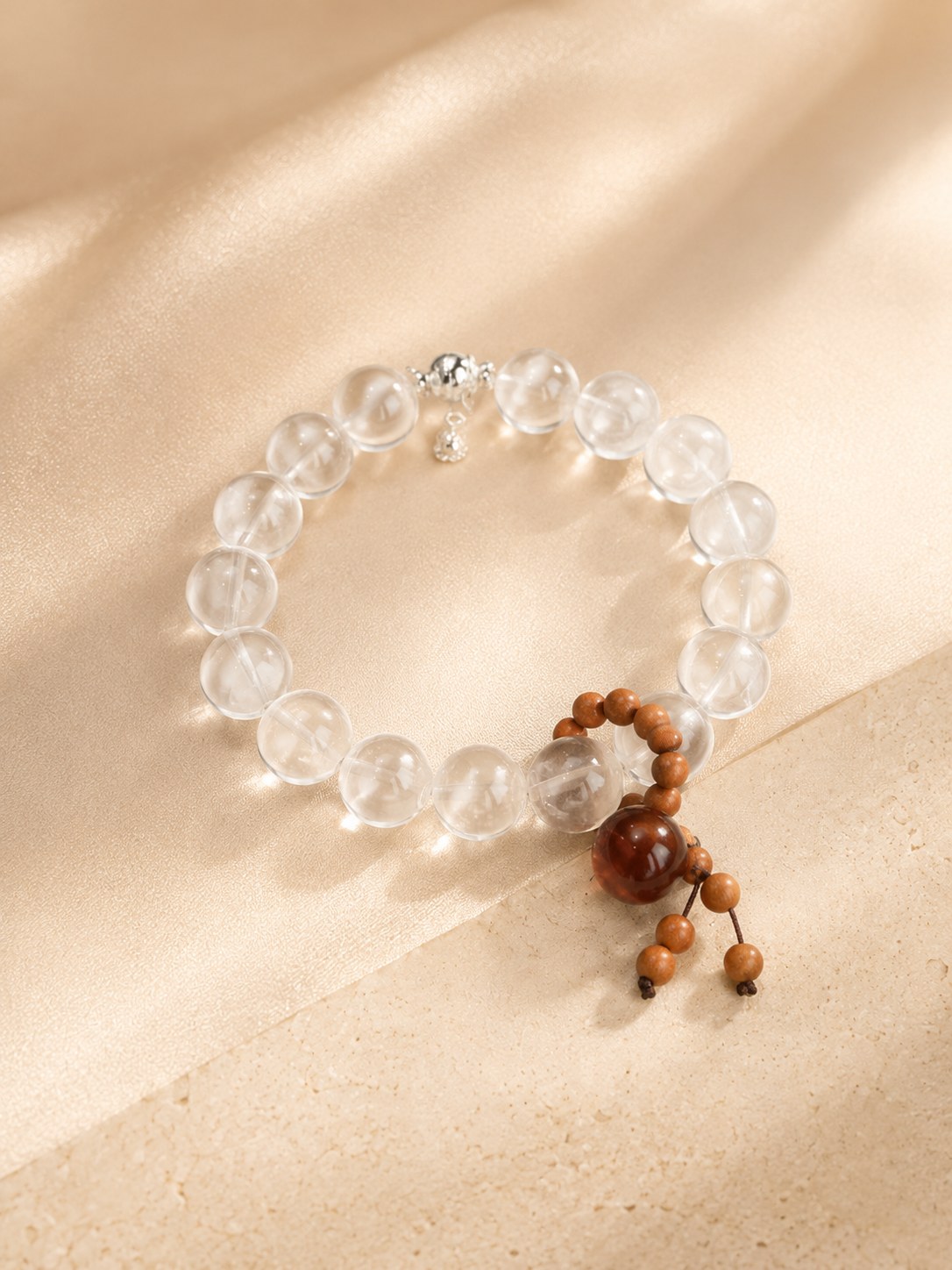 Clear crystal bracelet with warm brown charm on a soft beige surface